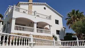 A two-story building with a white facade, multiple balconies with white railings, and a stone chimney. - Beautiful villa, swimming pool, tennis court, basketball court, garden, sea view, near beaches (El Vendrell)