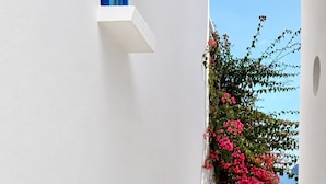 A narrow white-walled street with a blue door and a gate leading to a staircase.