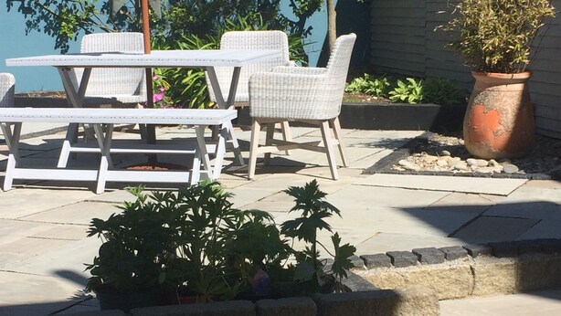 An outdoor patio with a table and chairs, a potted plant, and a stone wall. - Holiday home sleeps 6 central,  10 minute walk to golf course (Lahinch)
