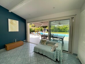A room with a bed, a bench, and a view of an outdoor swimming pool.