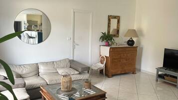 A living room with a sofa, a coffee table, a television, and a mirror.