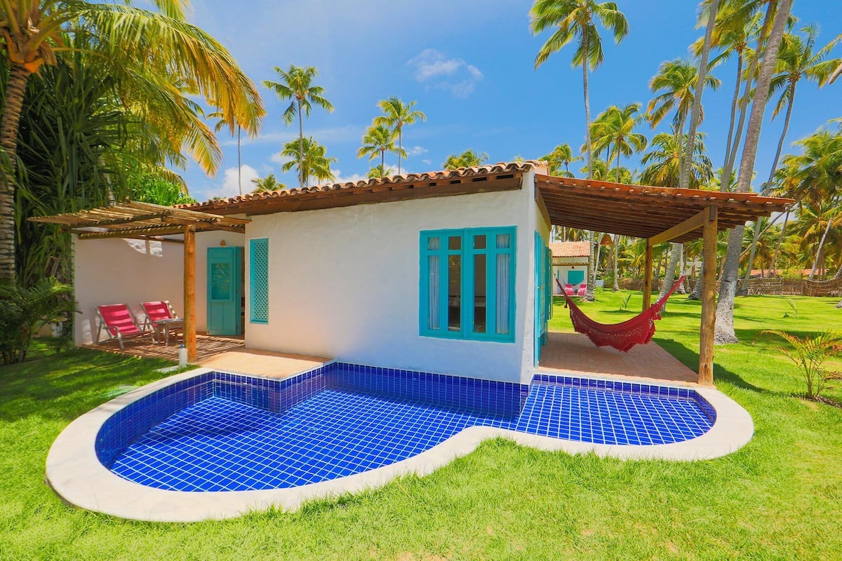 Una casa con piscina, hamaca y un patio con sillas.