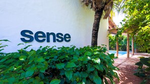 A sign with the word "Sense" on a white wall, surrounded by lush green foliage. - Pousada Patacho (Porto de Pedras)