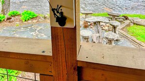 A wooden structure with a fishing rod mounted on a wall, overlooking a river and a picnic area. - Deep Creek Waterfront Home • Hot Tub • Pool Table • Minutes to Downtown & GSMNP (Bryson City)