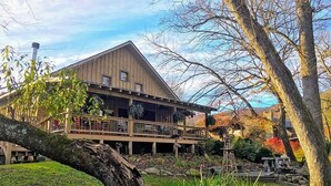 A rustic wooden building with a balcony, surrounded by trees and a garden. - Deep Creek Waterfront Home • Hot Tub • Pool Table • Minutes to Downtown & GSMNP (Bryson City)