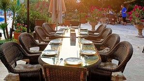 An outdoor dining area with wicker chairs and tables, surrounded by potted plants and flowers. - Hotel Palme Dalyan (Ortaca)
