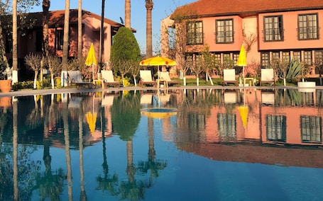 Una piscina al aire libre de temporada, sombrillas
