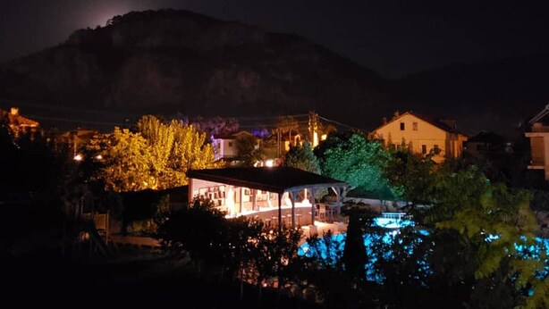 A nighttime view of a residential area with houses, a swimming pool, and a mountain in the background. - Hotel Palme Dalyan (Ortaca)