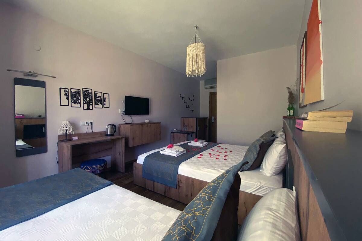 A hotel room with two beds, a desk, a TV, and a chandelier.