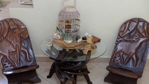 A round glass table with a wooden base, surrounded by two intricately carved wooden chairs. - BILLIAS HOUSE VOURVOUROU 4-room house, 8 people with great views of the sea (vourvourou)