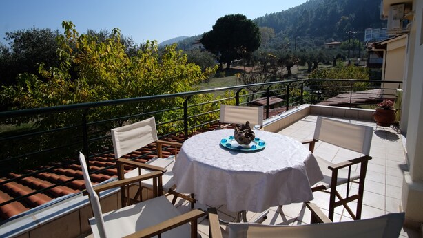 A terrace with a round table and chairs, overlooking a scenic landscape with trees and hills. - BILLIAS HOUSE VOURVOUROU 4-room house, 8 people with great views of the sea (vourvourou)