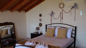 A bedroom with a bed, a nightstand, a mirror, and decorative wall hangings. - BILLIAS HOUSE VOURVOUROU 4-room house, 8 people with great views of the sea (vourvourou)