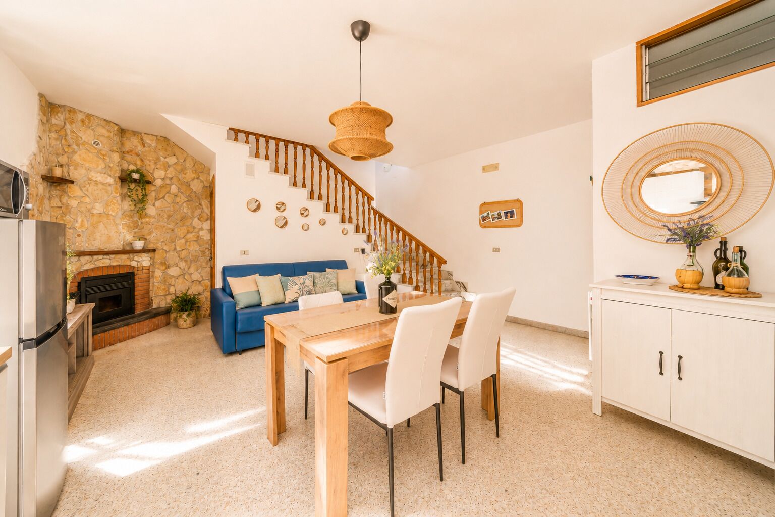 Eine moderne Küche mit Steinwand, blauem Sofa, Esstisch aus Holz und einer Treppe.