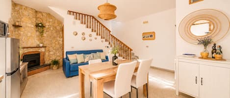 Una cocina moderna con pared de piedra, sofá azul, mesa de comedor de madera y una escalera.