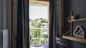 A room with a view of a balcony, a radiator, a chair, and a shelf with decorative items.