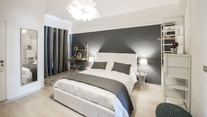A modern bedroom with a large bed, a bedside table, a lamp, a wardrobe, and a hanging light fixture.