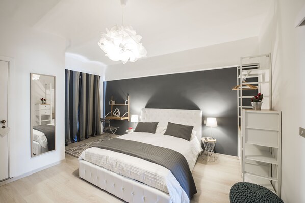 A modern bedroom with a large bed, a bedside table, a lamp, a wardrobe, and a hanging light fixture.