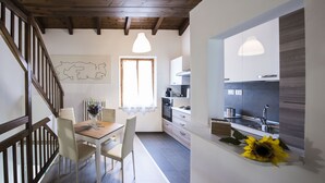 A modern kitchen with wooden beams, a dining area with a table and chairs, and a large window.