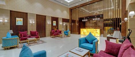 A spacious lobby with plush seating, a reception desk, and a decorative chandelier.