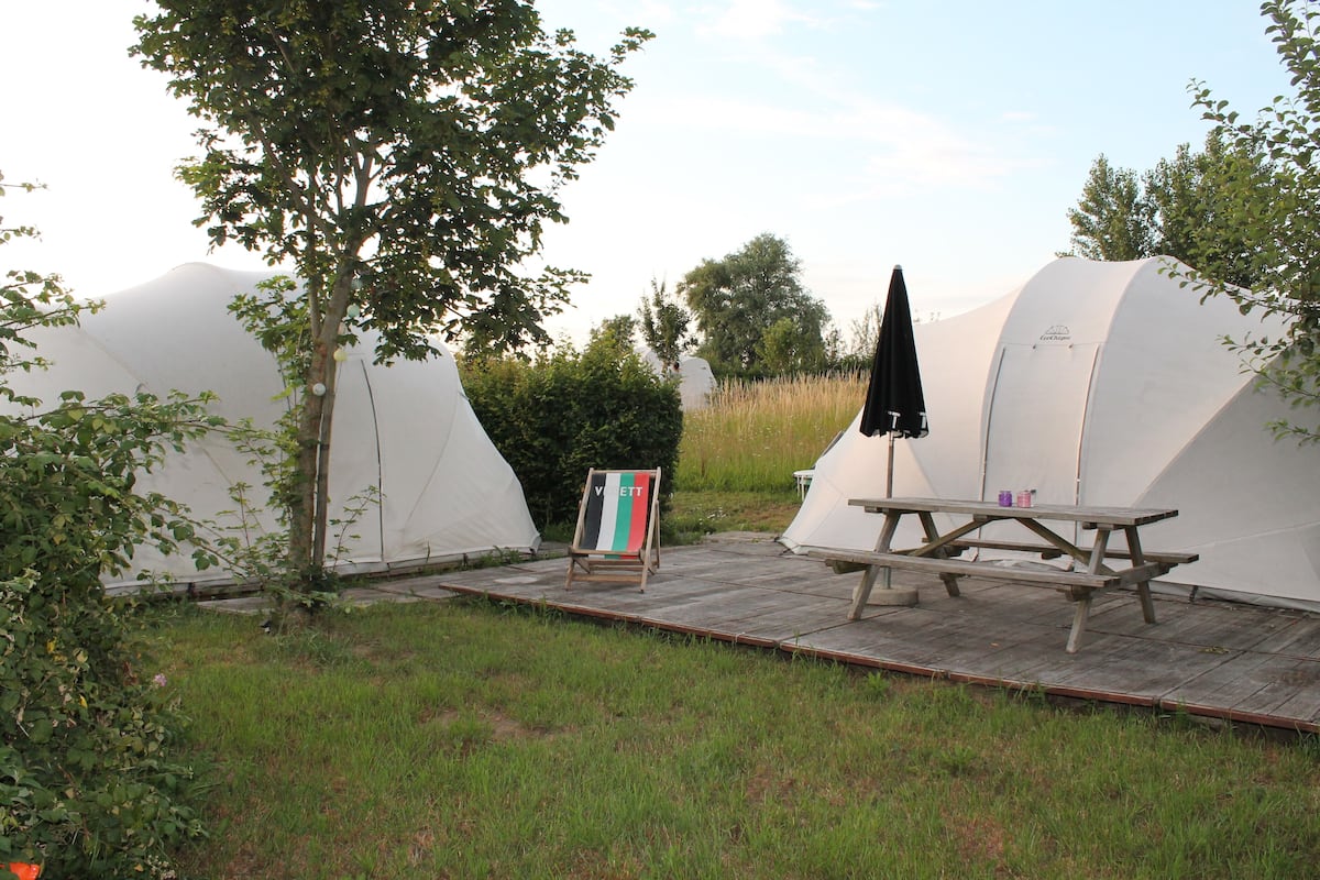 Un camping con tiendas de campaña, una mesa de picnic y un cartel.