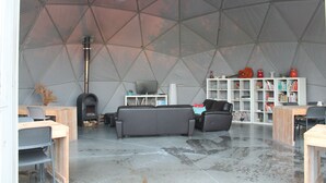 A spacious living area with a large, geometric dome ceiling, a fireplace, a sofa, a television, and a bookshelf. - Ecochique (Heuvelland)