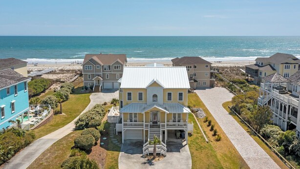 A coastal residential area with a prominent house featuring a front porch, a driveway, and a view of the beach. - Oceanfront, private pool,hot tub,elevator located in the Dolphin Ridge community (Emerald Isle)