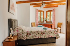 Ein Schlafzimmer mit Bett, Nachttisch, Lampe, Fenster und Vorhängen.