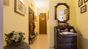 A hallway with a wooden dresser, a mirror, and a vase with flowers. - Dreaming of You Bed & Breakfast (Assisi)