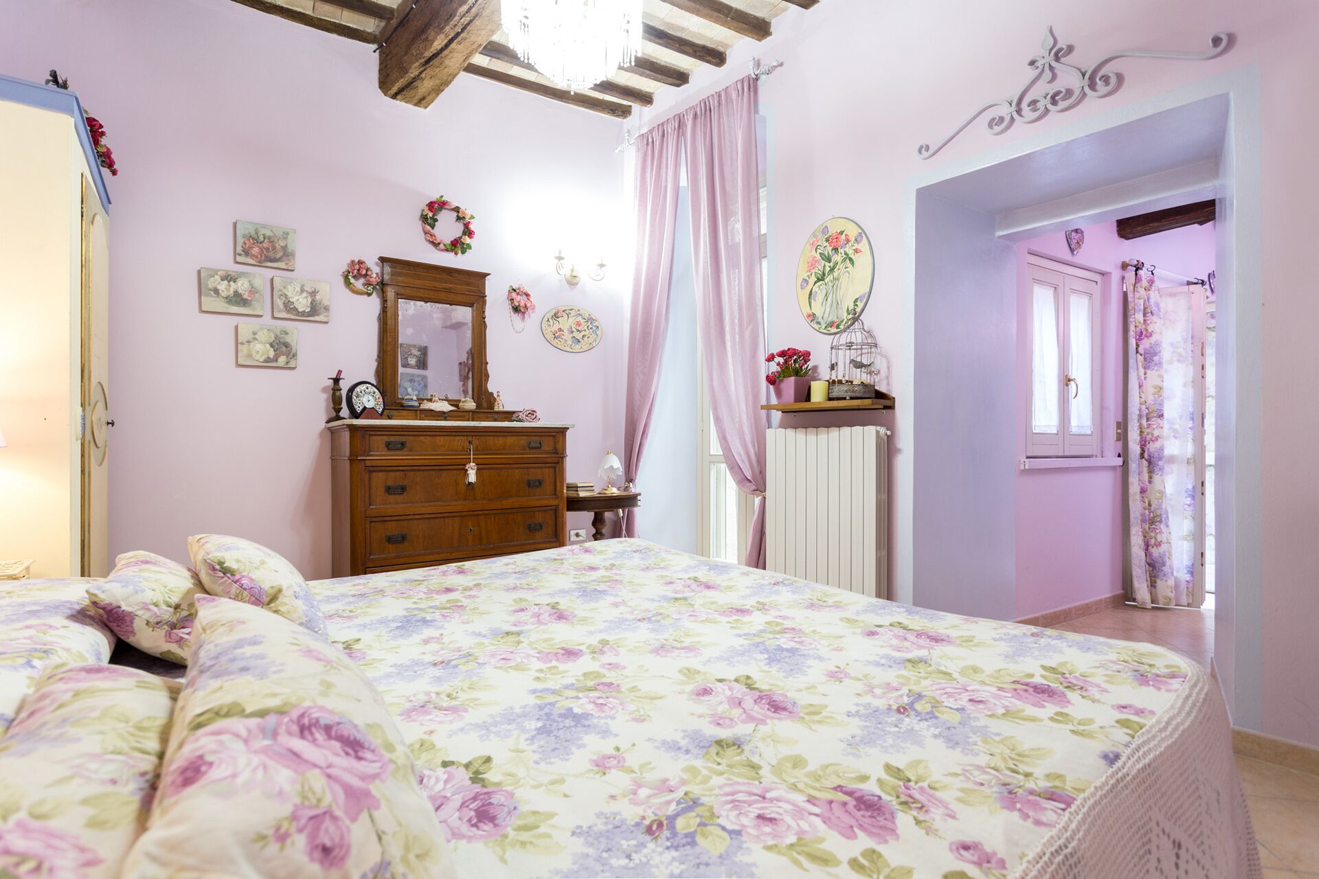 Una camera da letto con copripiumino floreale, una cassettiera in legno e uno specchio.