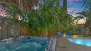 A backyard with a hot tub, a swimming pool, and a wooden fence. - Pirates Cove ~ Heated Pool, Hot Tub, Game Room & 6-Seater Golf Cart (Panama City Beach)