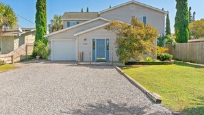 A two-story house with a front garage, a blue door, and a well-maintained lawn. - Pirates Cove ~ Heated Pool, Hot Tub, Game Room & 6-Seater Golf Cart (Panama City Beach)