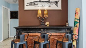 A bar area with a dark counter, two wall-mounted lamps, and a framed fish illustration above. - Pirates Cove ~ Heated Pool, Hot Tub, Game Room & 6-Seater Golf Cart (Panama City Beach)