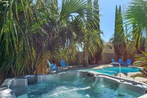 A hot tub surrounded by palm trees and blue chairs.
