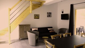 Uma sala de estar moderna com uma escada, um sofá, uma mesa de jantar e cadeiras.