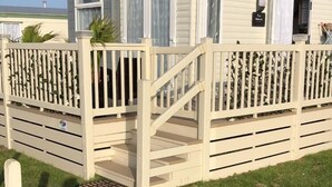 Une maison mobile dotée d’un porche couvert, d’une petite terrasse et d’une structure à un seul étage.