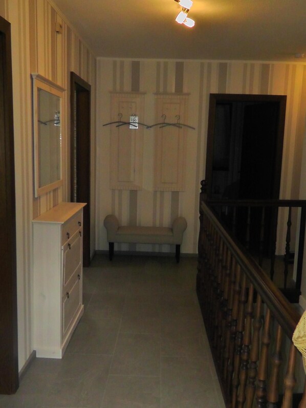 Un pasillo con un banco de madera, un armario blanco y una escalera con barandilla de madera.