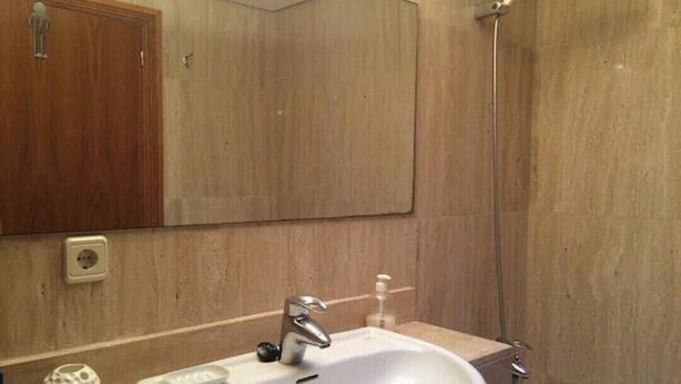 Une salle de bain avec un lavabo blanc, un miroir, une douche et un meuble en bois.