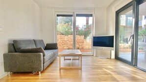Ein modernes Wohnzimmer mit grauem Sofa, einem Holztisch und einem Flachbildfernseher.