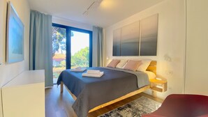 Ein modernes Schlafzimmer mit einem großen Bett, einem Schreibtisch und Blick ins Freie.