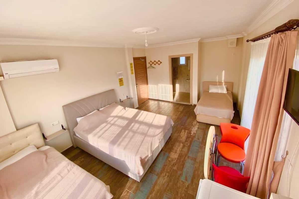 A hotel room with two beds, a small table, and a chair.