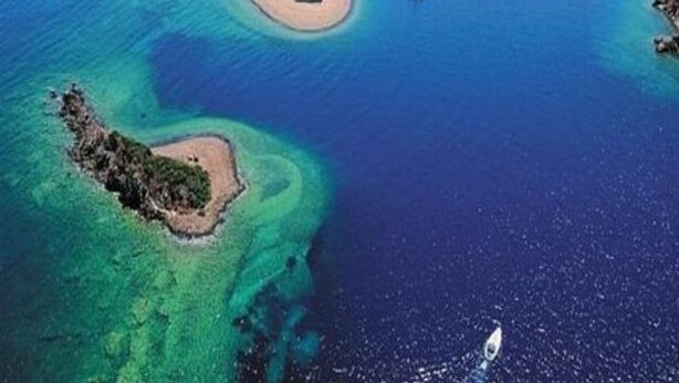 Eine Luftaufnahme einer Küstenregion mit mehreren Inseln, klarem blauen Wasser und Booten.