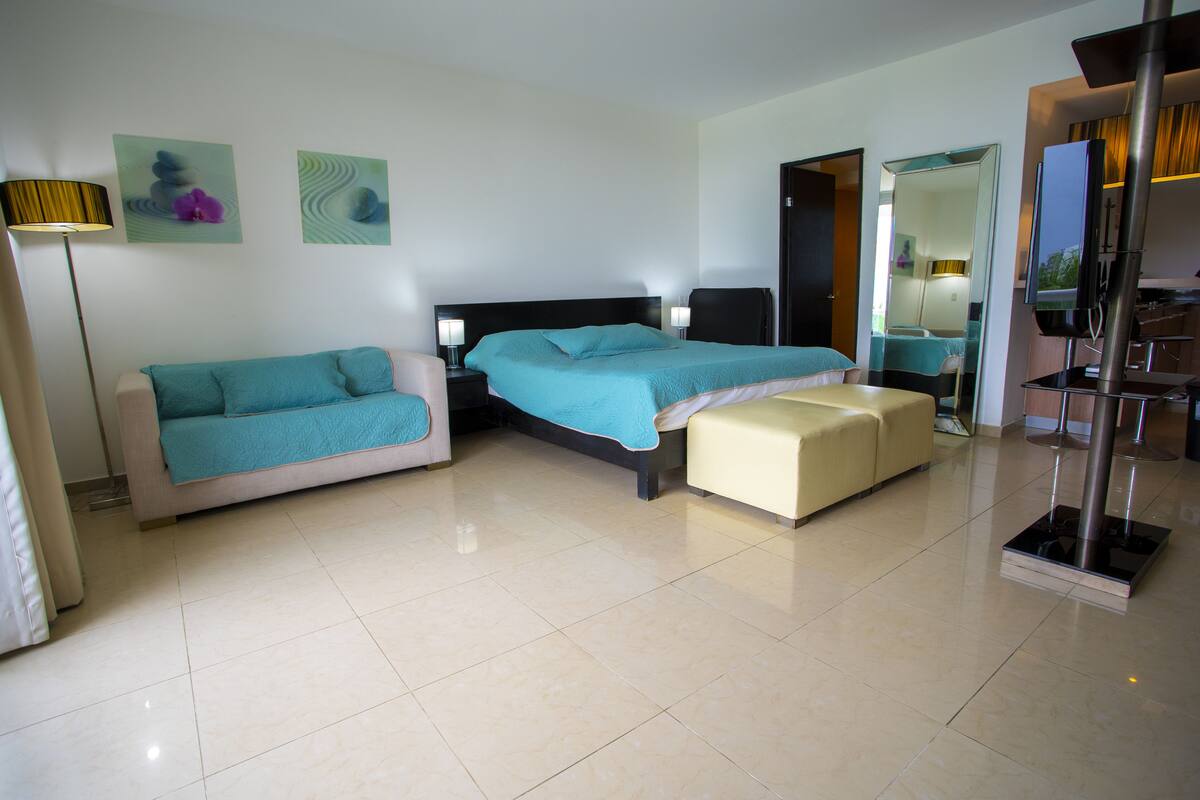 Ein modernes Hotelzimmer mit Bett, Sofa, kleinem Tisch und Spiegel.