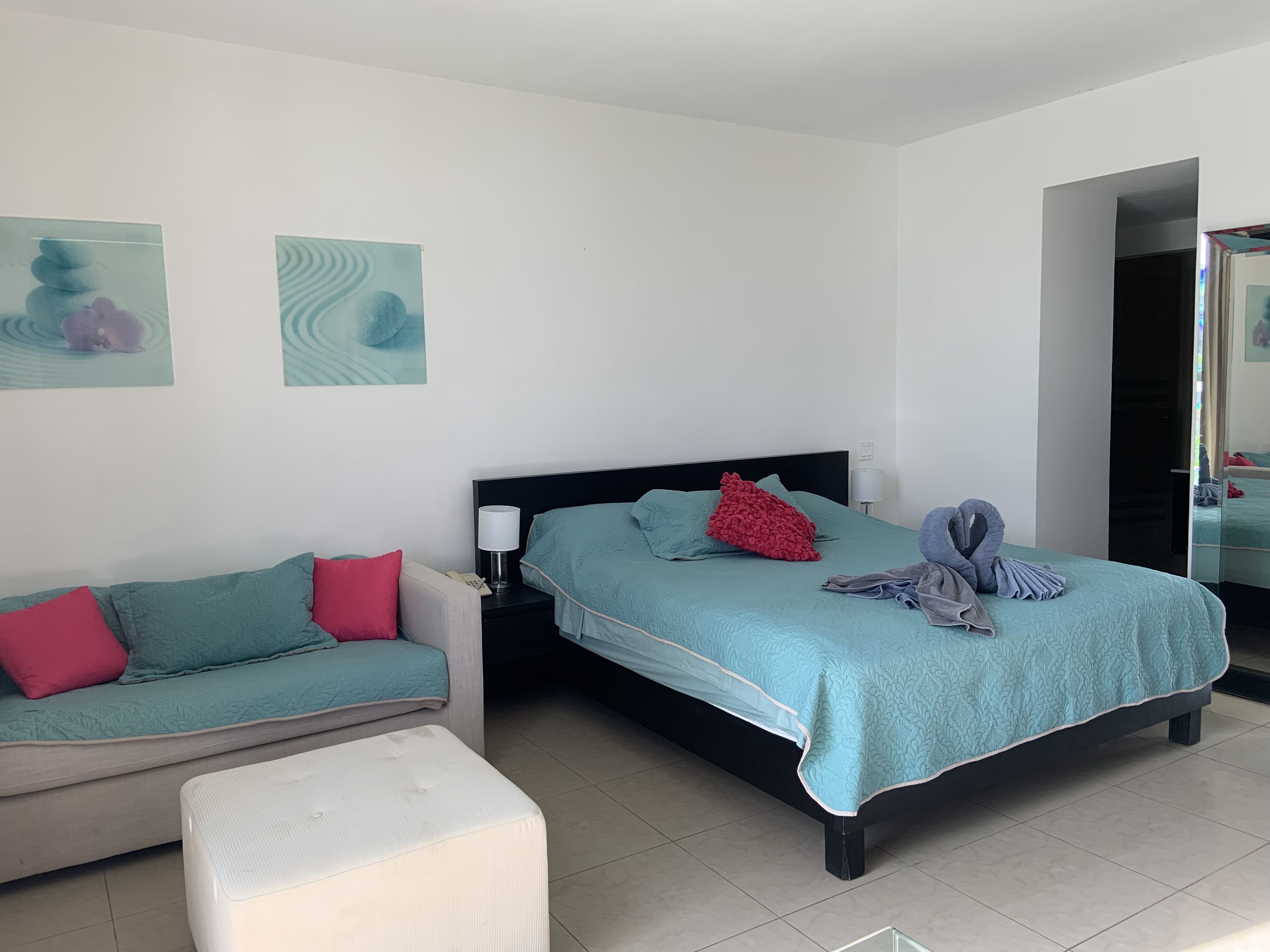 Une chambre à coucher avec un lit, une table de chevet, une lampe, un canapé et une petite table.