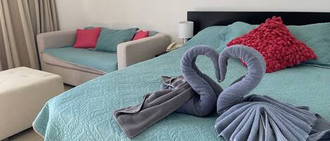 Una habitación de hotel con una cama, dos sofás y una mesita de noche.