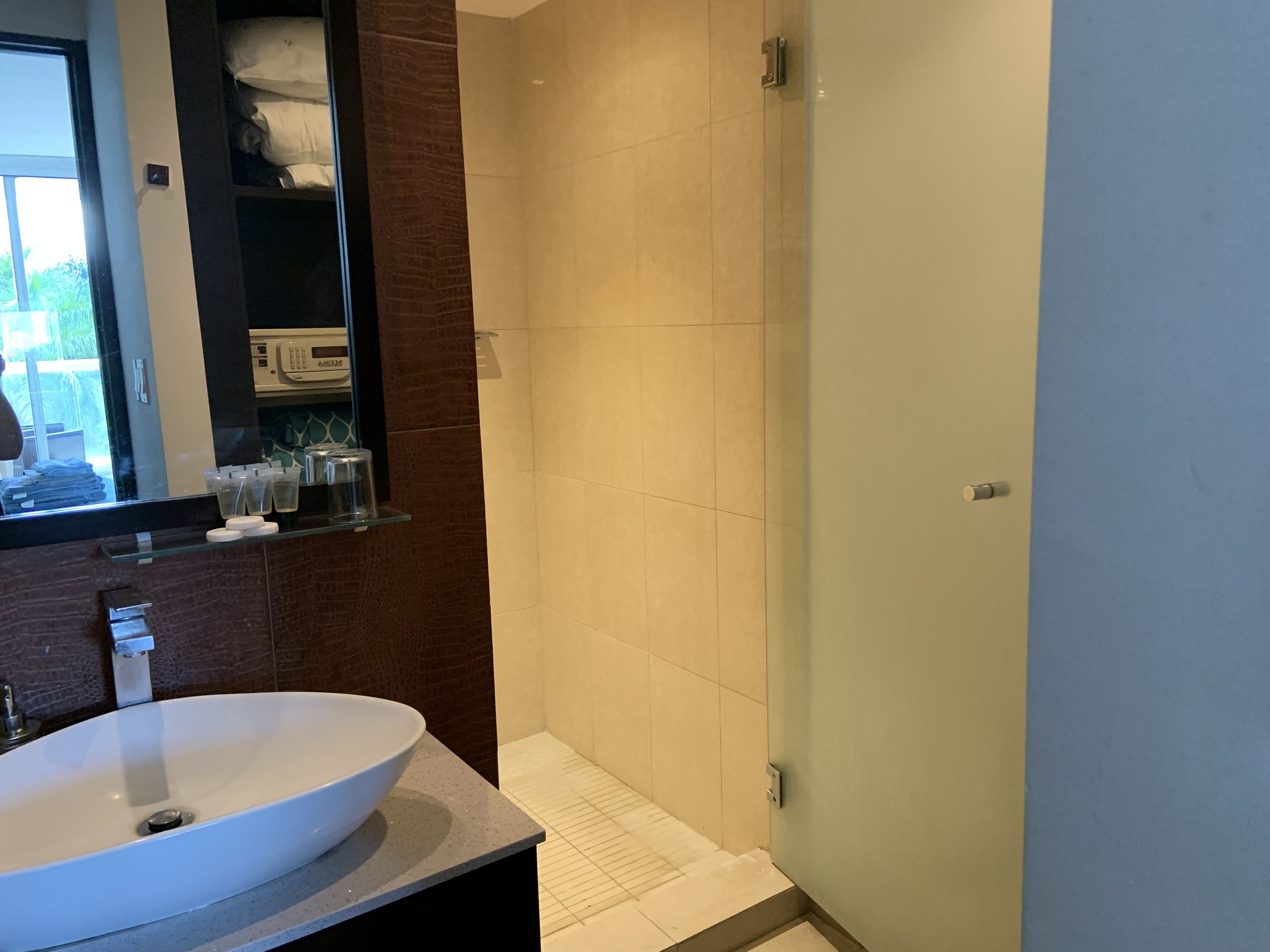 A modern bathroom with a large white sink, a mirror, and a shower area.