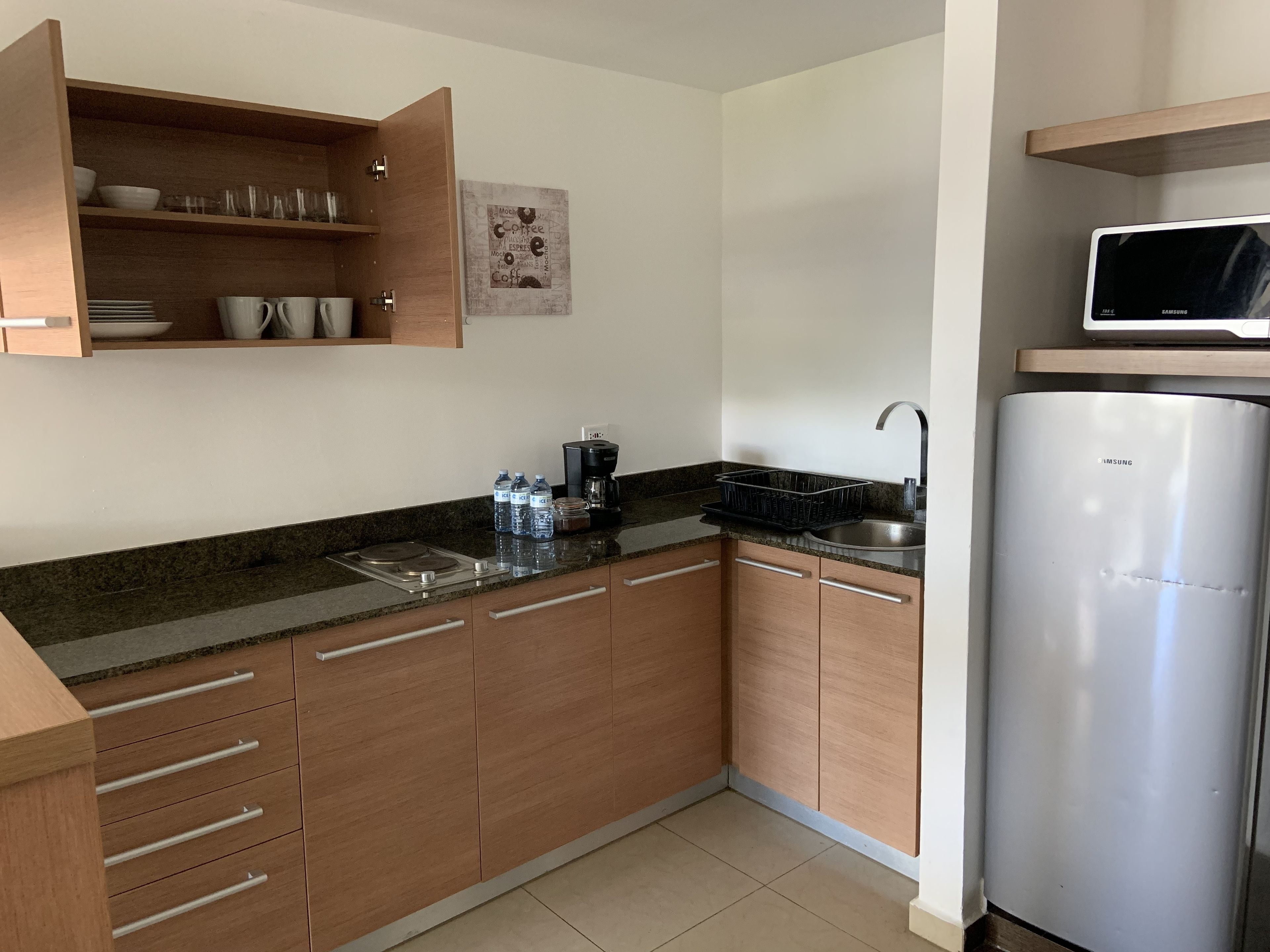 Una cocina moderna con gabinetes de madera, un refrigerador de acero inoxidable, un microondas y una cafetera.