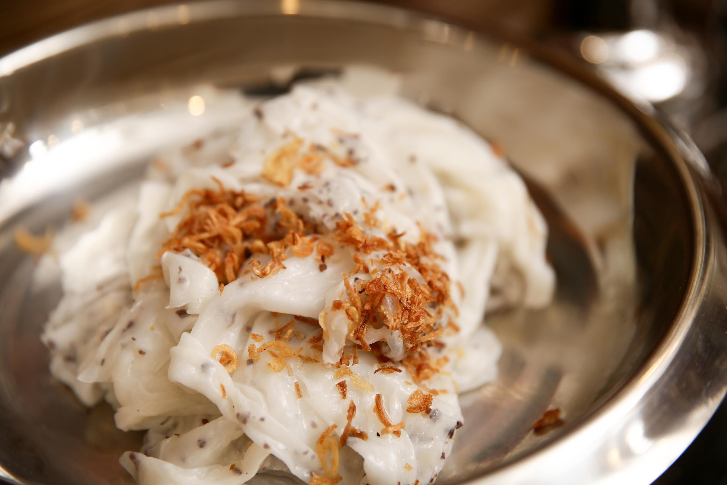 A bowl of food with a creamy white sauce and fried onions on top.