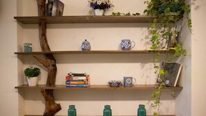 Una estantería de madera con libros, objetos decorativos y una planta en maceta.