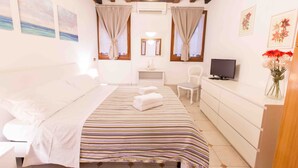 Une chambre à coucher avec un lit, une télévision, un bureau et une commode.