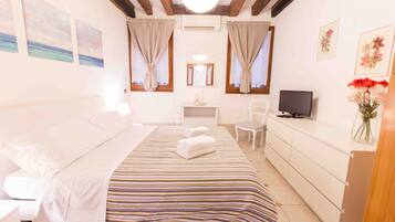 A bedroom with a bed, a TV, a desk, and a dresser.